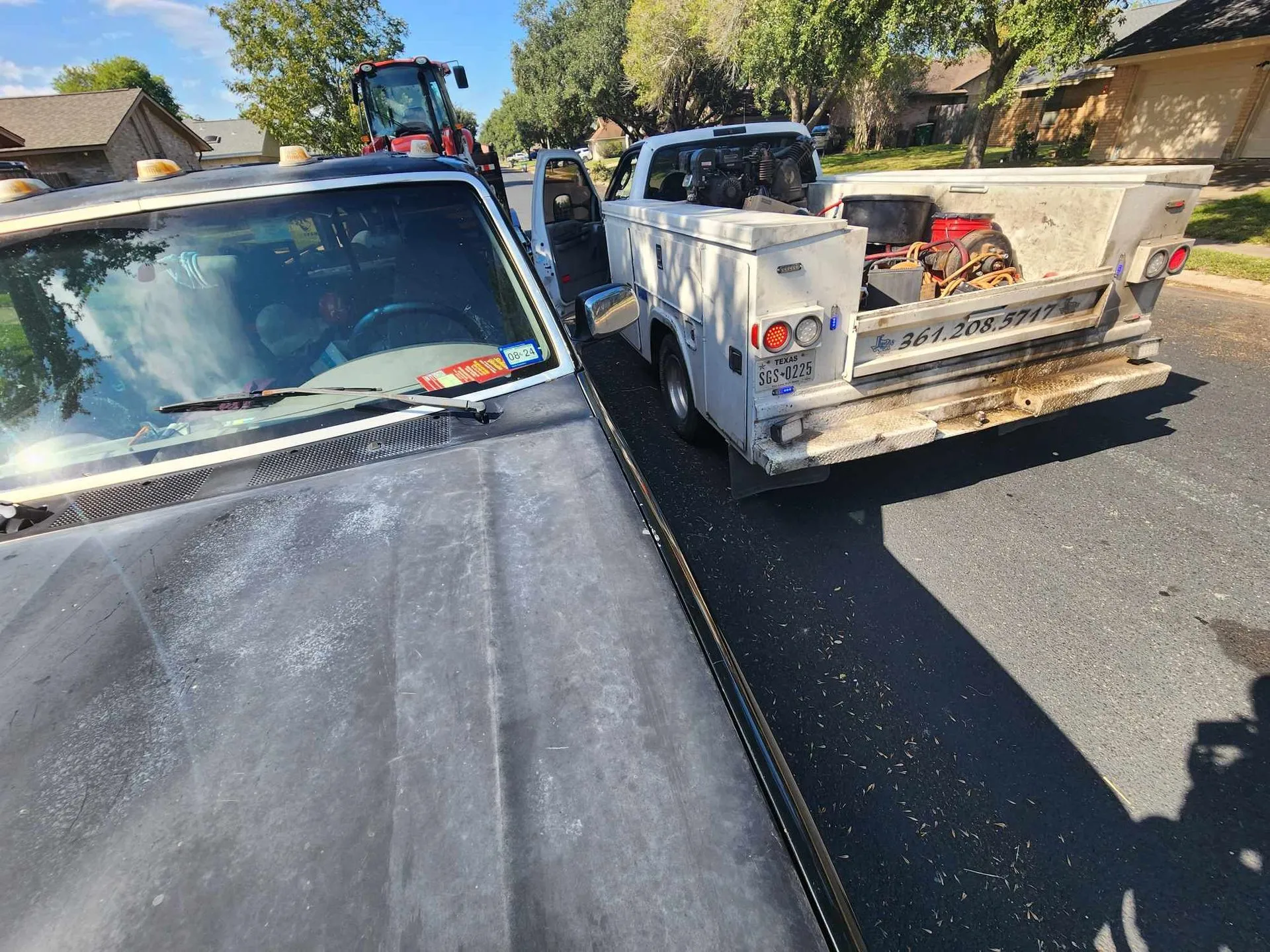 Service truck parked next to a utility truck on a residential street.