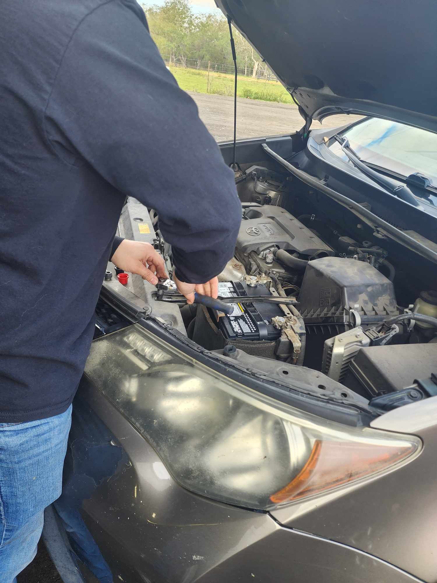 Person working on a car engine outdoors