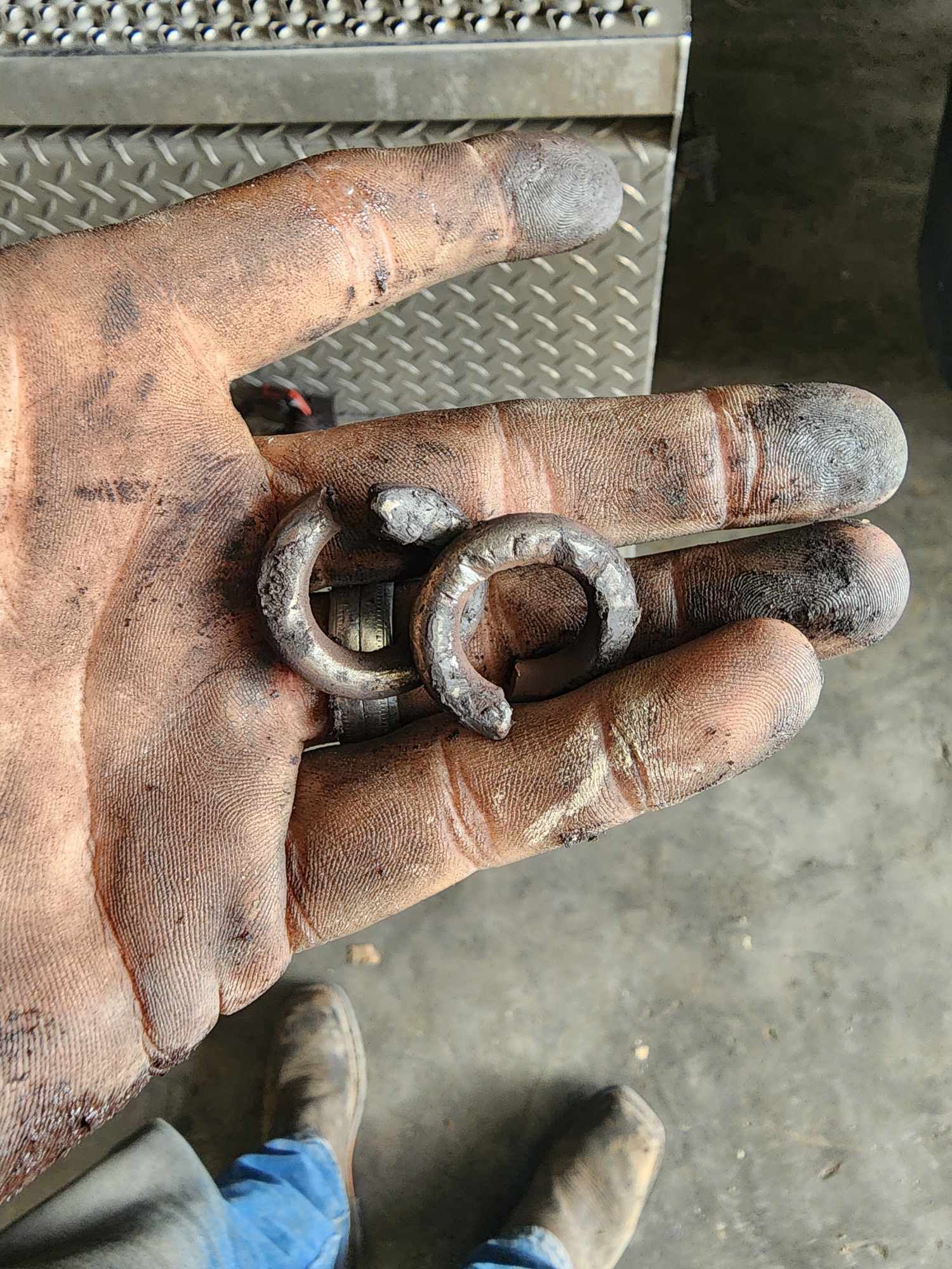Hand holding two worn metal clips.
