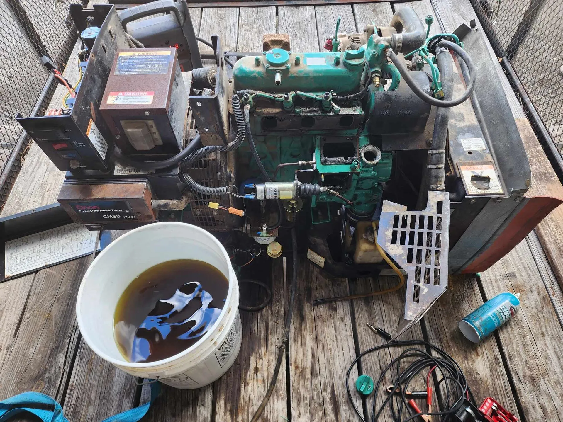 Diesel engine on a wooden surface with a bucket of oil and tools.