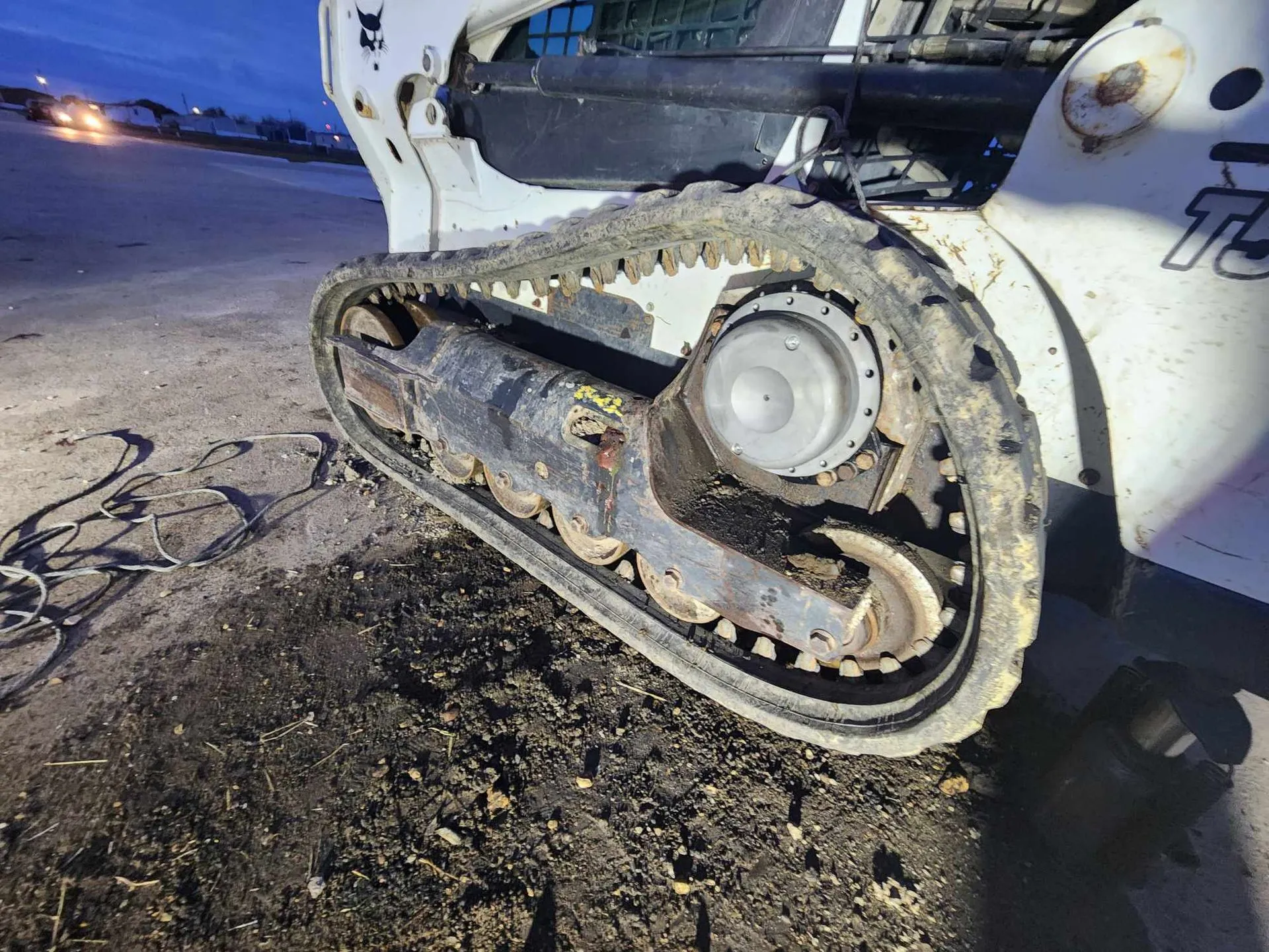 Bobcat track loader covered in dirt on a muddy surface.