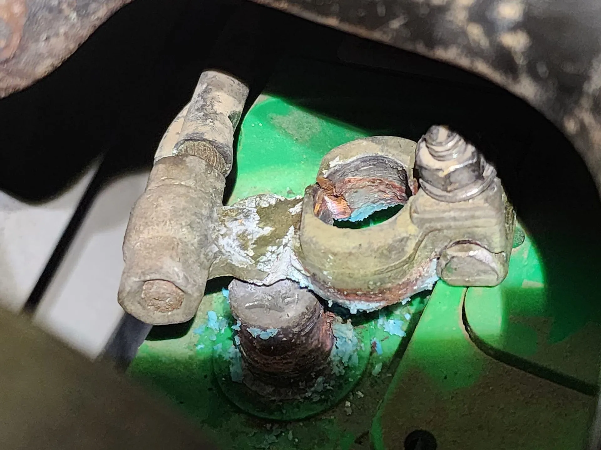 Corroded car battery terminal with white and blue residue.
