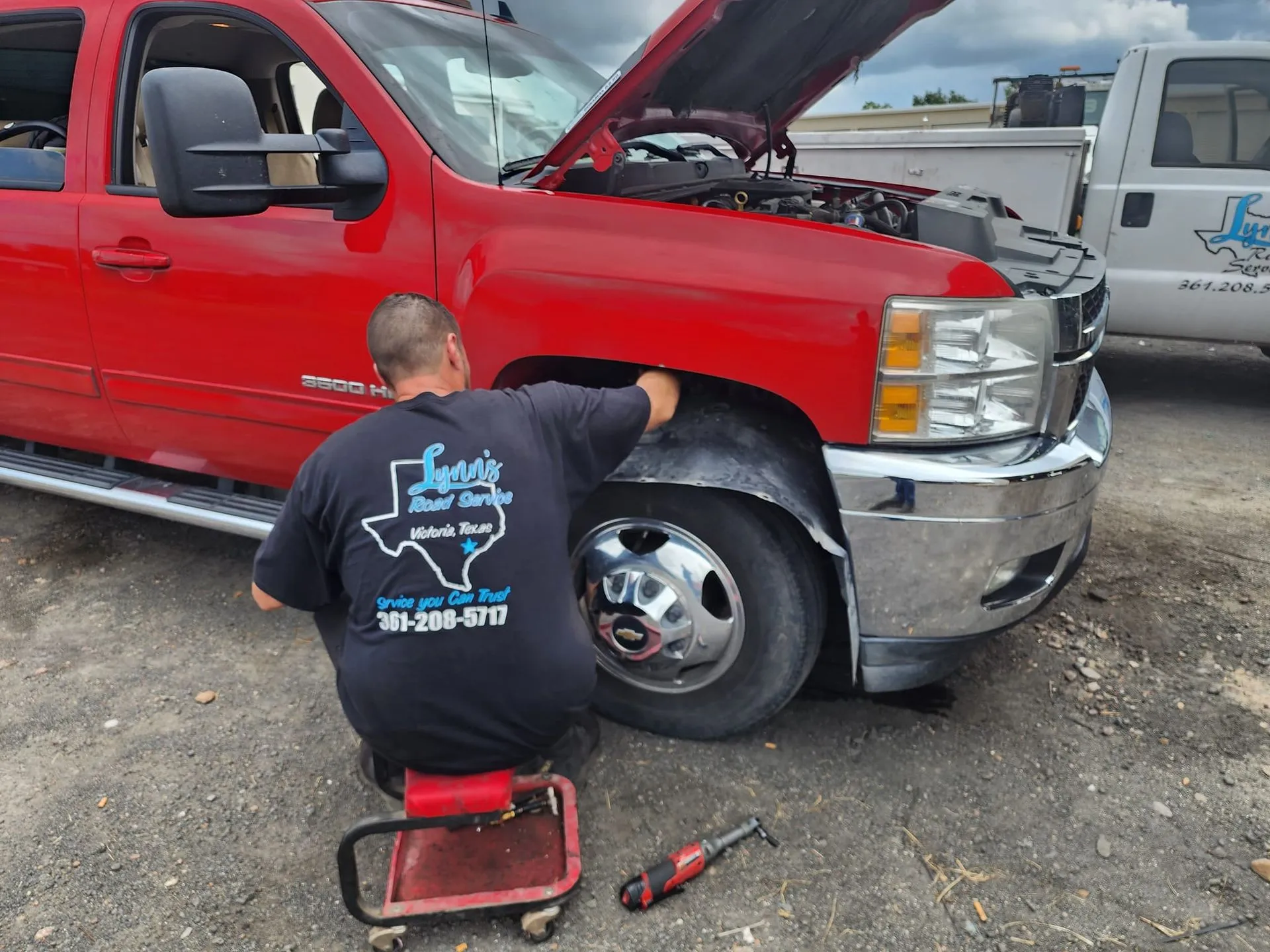 Man working on a red truck's wheel well