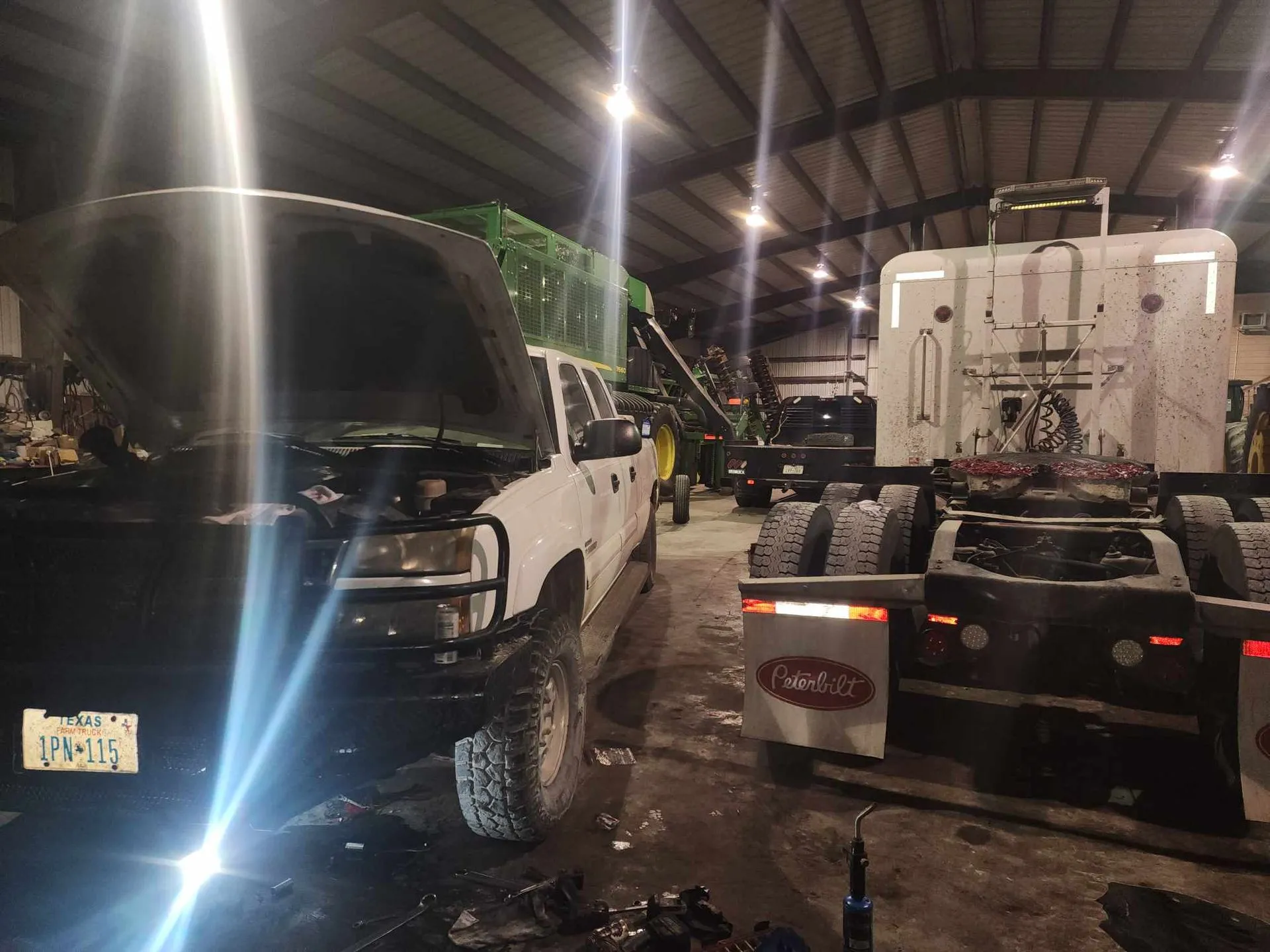 White truck with the hood open next to a semi truck in the shop.