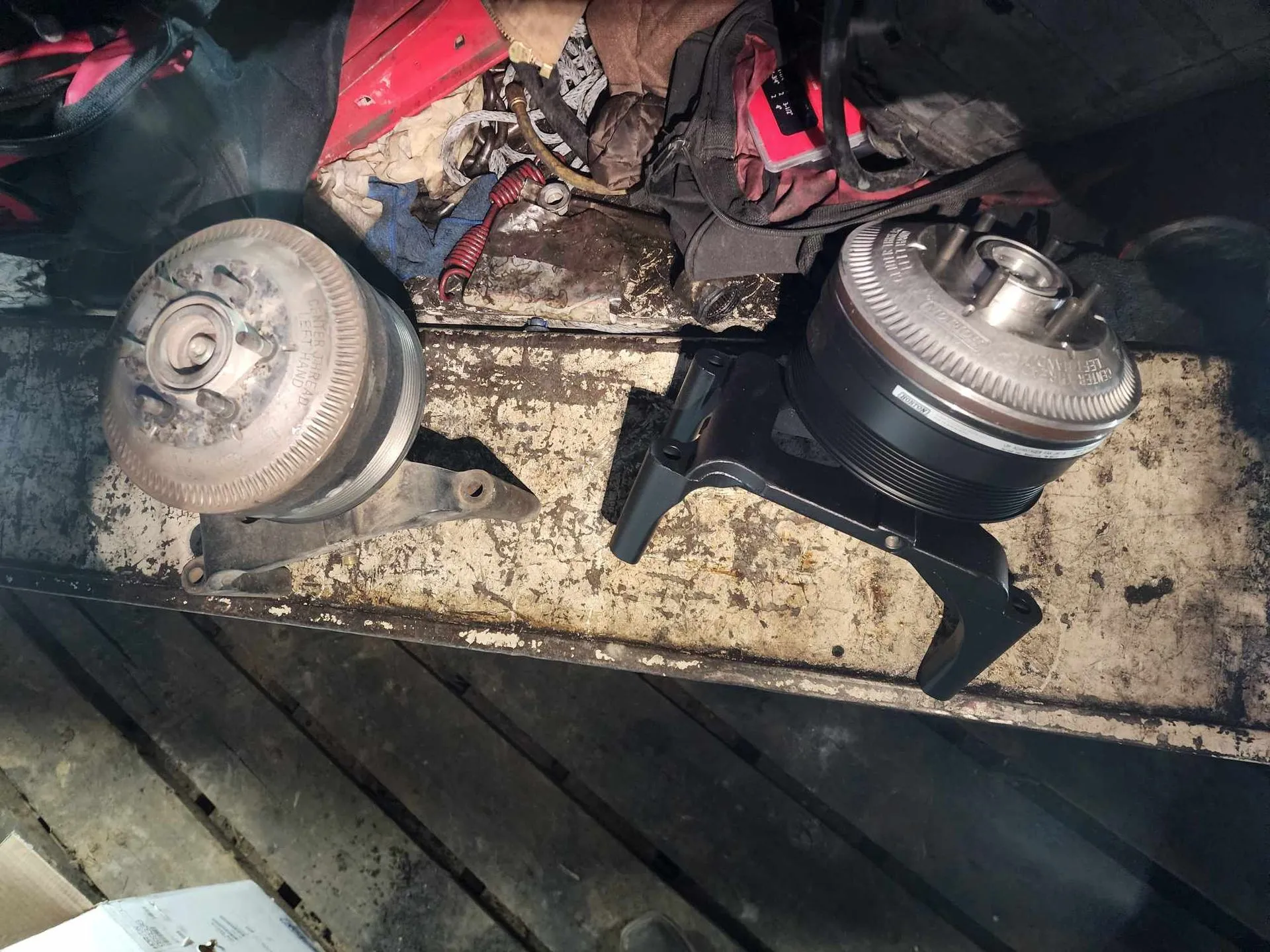 Two metal vehicle parts on a dirty surface.
