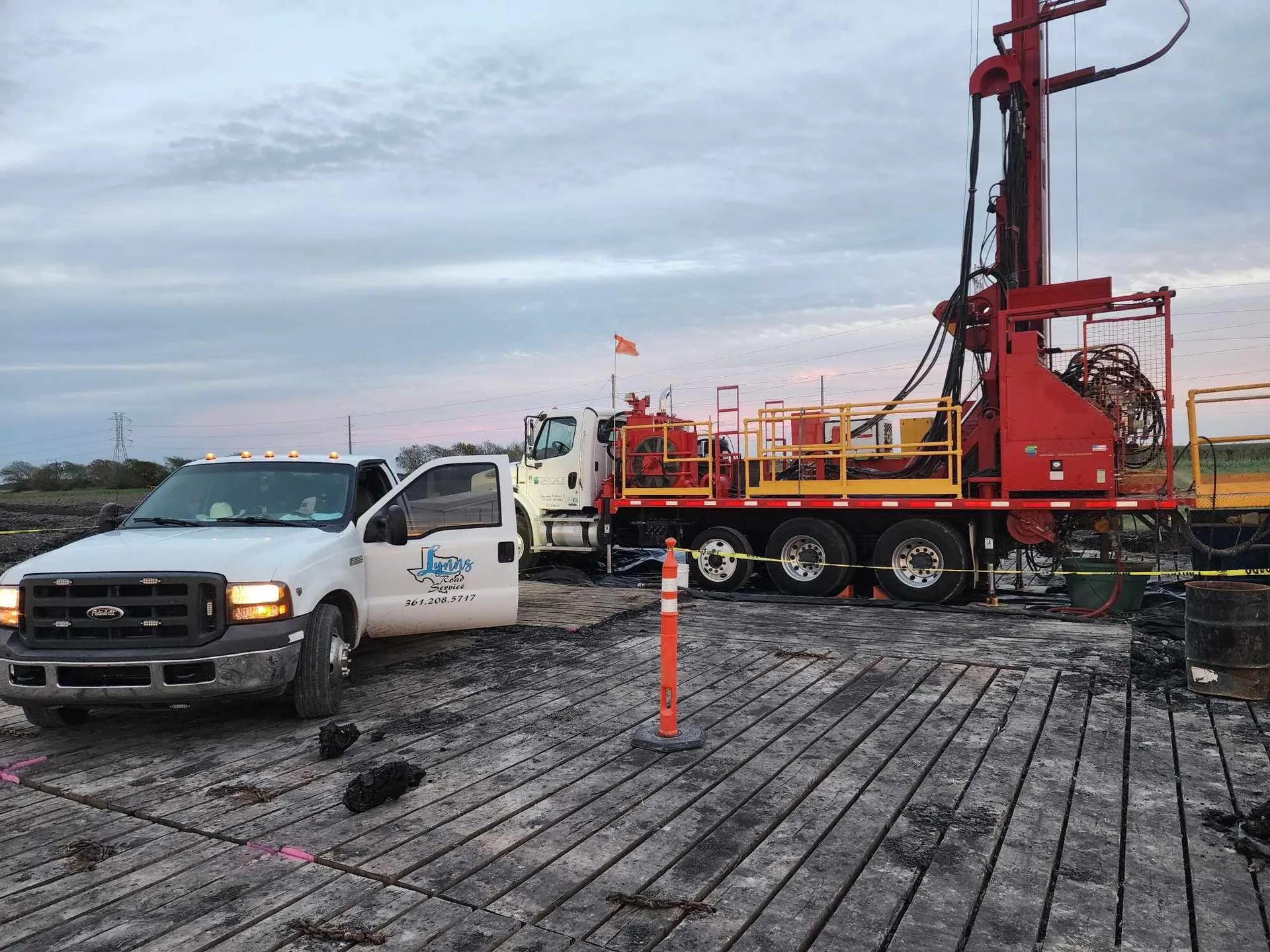 A white truck and drilling rig on a wooden platform.