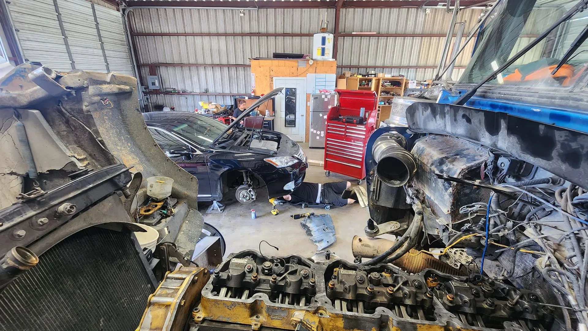 Burned-out vehicles inside a cluttered garage after a fire.